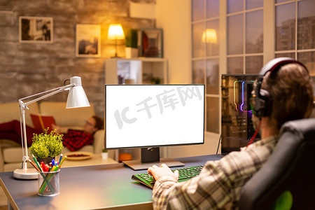 职业游戏玩家的后视图看电脑与孤立的模拟屏幕