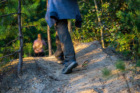 鞋子夏季摄影照片_在夏季森林的某个地方，穿着鞋子和裤子徒步旅行的人腿，特写镜头有选择的焦点。