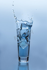 冰块杯水摄影照片_落入杯水的冰块