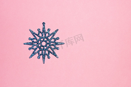 粉红色雪花摄影照片_粉红色背景中的蓝色雪花，圣诞背景的复制空间
