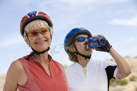 老年背景摄影照片_背景中有朋友喝水的快乐老年女性的画像