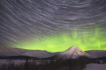 夜空中的星迹和雪山的绿色北极光