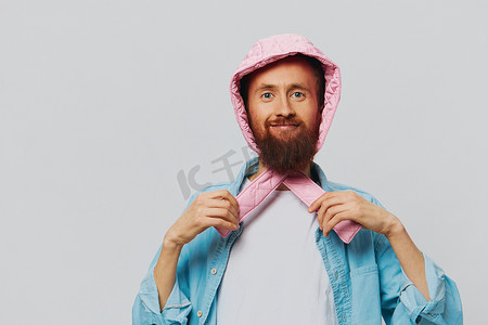 粉红色帽子摄影照片_在浅灰色背景上戴着粉红色帽子肖像的滑稽男人。