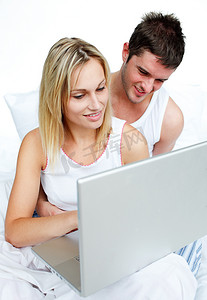 夫妇在床上使用笔记本电脑