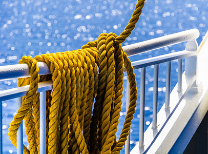 互补摄影照片_黄色编织绳索搭在船栏杆上