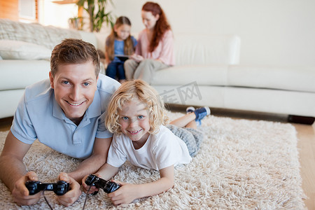 父亲和儿子在地板上玩电子游戏