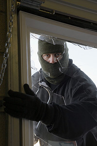 一个蒙面小偷从窗户闯入房子的肖像