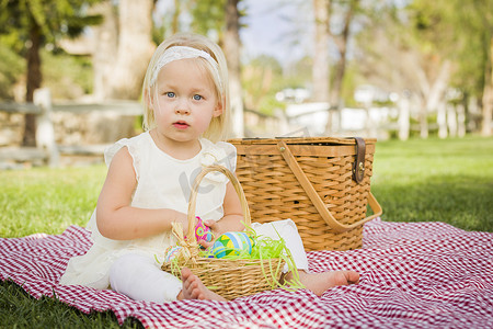可爱的小女孩在野餐毯上享受她的复活节彩蛋