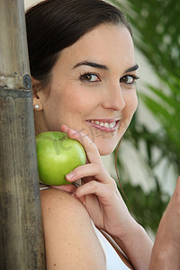 一个拿着苹果靠在竹签上的黑发女人