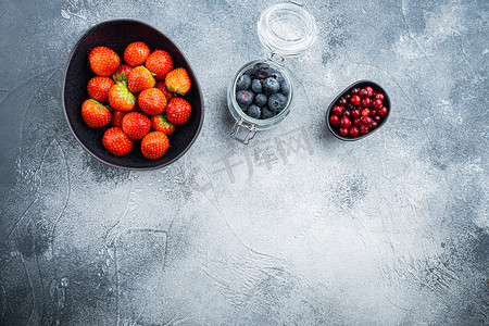 蓝色文字纹理摄影照片_成熟的草莓、蔓越莓和蓝莓放在碗里，平躺着，有文字空间，有纹理的背景