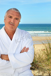 海边酒店摄影照片_海边穿着毛巾长袍的中年男子