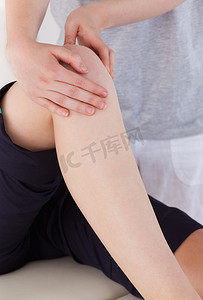 女按摩师摄影照片_一位女按摩师在一位运动女性的膝盖上按摩的肖像