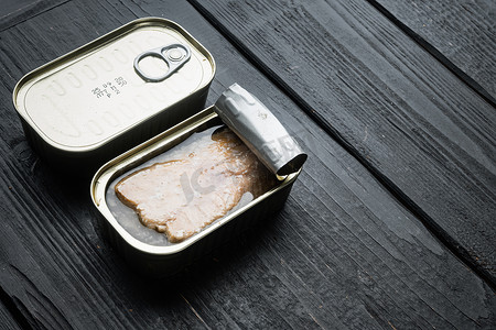 阿拉斯加三文鱼摄影照片_罐装野生阿拉斯加鲑鱼罐头，装在锡罐中，黑色木桌背景，带有复制空间和文本空间