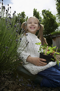 一个小女孩在花园里对着天空拿着植物的低角度肖像