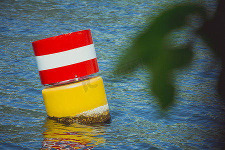 红色黄光摄影照片_蓝光中的黄红白钢航海浮标