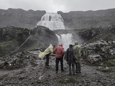 一群身穿彩色雨衣的游客观看冰岛西峡湾最大的 Dynjandi 瀑布，复古的单色外观