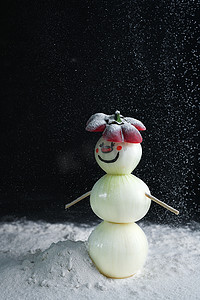 一个用珍珠洋葱做的雪人站在雪地上。