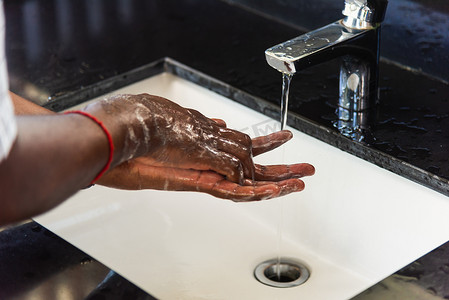男人的手在水槽里用肥皂和水搓揉