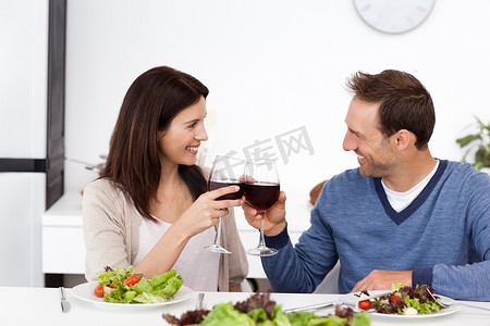 可爱的情侣在午餐时碰杯红酒