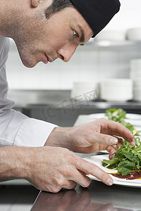 一位男厨师在厨房准备沙拉的特写侧视图