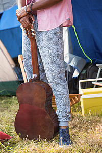 时髦的人在露营地拿着吉他