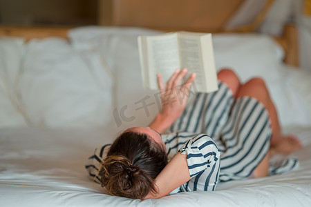 台灯看书摄影照片_美丽的女人在床上看书放松