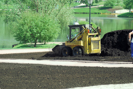 春季在城市公园工作的小型挖掘机抓斗