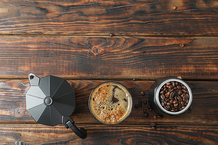 木桌上放着一杯新鲜咖啡、咖啡机和咖啡豆的平铺组合物，还有文字空间