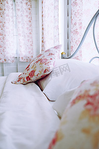花卉图案摄影照片_明亮的卧室内饰，床上有花卉图案枕头
