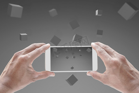 拿着手机3d摄影照片_使用手机的人的抽象技术 商人拿着带有灰色屏幕的智能手机 社交媒体在手机上使用飞行的 3d 盒子 在灰色背景下的网络空间设计