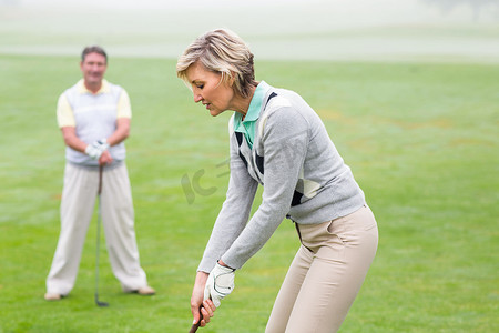 女高尔夫球手为伴侣观看的一天开球