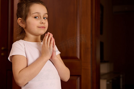 特写肖像漂亮的小女孩，在练习瑜伽时双手合十，微笑着看着镜头