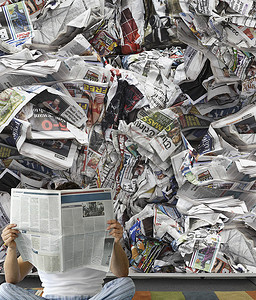 环保报纸摄影照片_靠着一堆纸看报纸的人