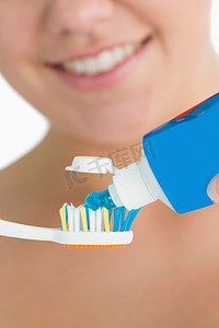 微笑的女人把牙膏放在牙刷上