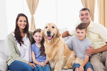 幸福的家庭和金毛猎犬坐在沙发上