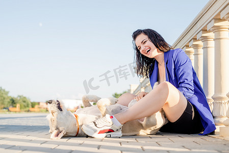 年轻快乐的女人在公园里和她的狗玩耍