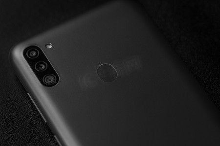 手机背面背面摄影照片_选择性关注新款智能手机三星 Galaxy M11 三重摄像头和指纹传感器的背面。