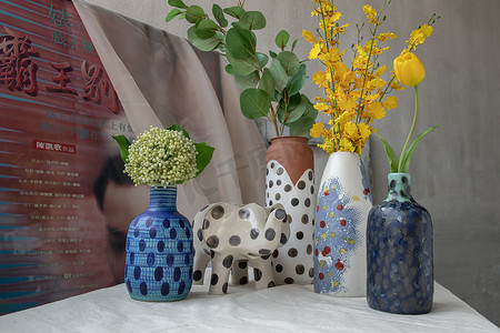 白色纹理桌布上手工制作的许多花束，各种不同的陶瓷波尔卡圆点花瓶和大象形陶瓷。