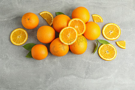 许多成熟的橙子和树叶，灰色桌子上有文字空间，顶视图