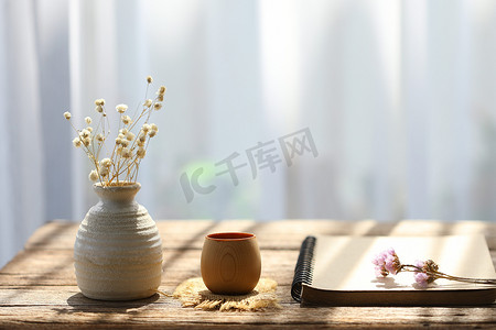 带笔记本的陶罐干花和质朴的棕色木桌室内现代家居装饰中的花