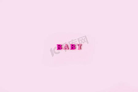 BABY 这个词是由浅粉色背景上的木制字母组成的。