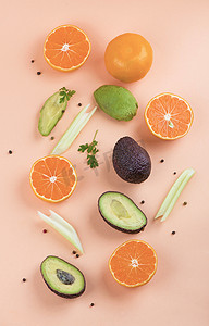 橙色背景下由橙子、芹菜和鳄梨制成的创意夏季图案。