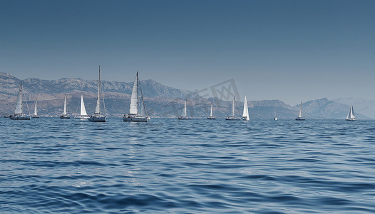 美丽风车摄影照片_背景是帆船的美丽海景，地平线上的帆船比赛，帆船赛，激烈的比赛，鲜艳的色彩，带风车的岛屿