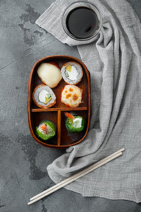 日式平铺摄影照片_带筷子的日式便当午餐盒，灰色石头背景，顶视图平躺