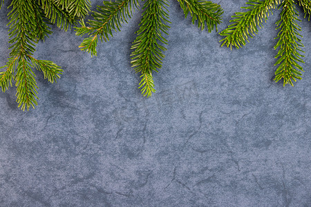 蓝色主题背景摄影照片_圣诞主题、质地、背景，顶部是诺德曼冷杉的树枝，深灰色蓝色大理石背景，有文字的自由空间。