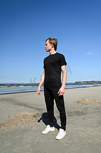 黑衣服和白色鞋子的年轻男性站立在海滩