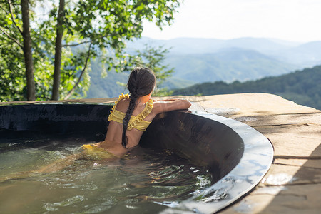 花瓣水泡澡摄影照片_小女孩在山上泡热水澡，夏天