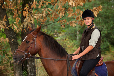 骑马穿过林地的年轻女子
