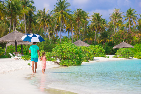 带伞的女孩摄影照片_父亲和带伞的小女孩在海滩上躲避阳光