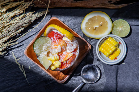 热带新鲜水果沙拉配牛奶和燕麦片，放在玻璃杯中，在深色背景下配上玉米。